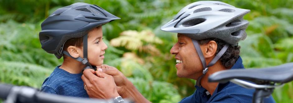 père attachant un casque de vélo à son enfant