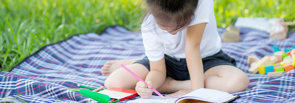 	enfant qui révise l&apos;été avec un cahier de vacances