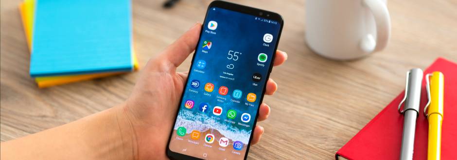 personne à son bureau, avec un smartphone en main