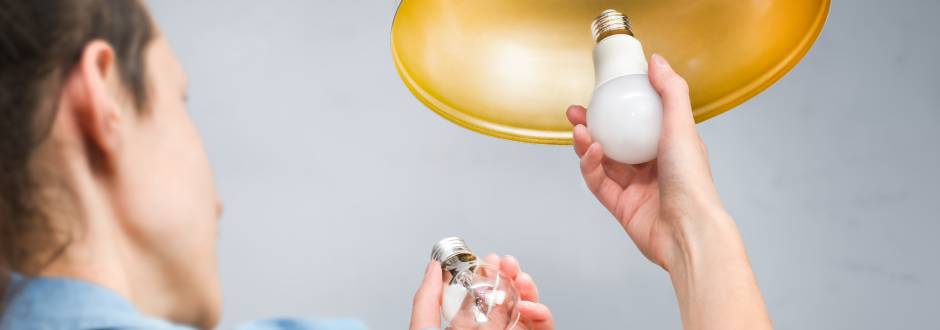 personne en train de visser une ampoule LED à une lampe