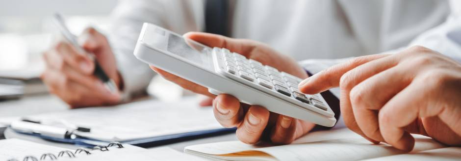 personne vérifiant avec sa calculatrice le montant de sa déclaration d’impôts